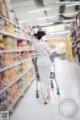 A woman wearing a face mask walking down a grocery store aisle.