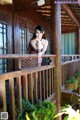 A woman standing on a wooden balcony next to a window.