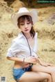 A woman in a white shirt and a cowboy hat sitting on a hay bale.