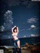 A woman in a bikini standing on a beach next to the ocean.