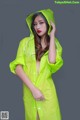 A woman in a yellow raincoat is posing for a picture.