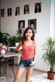 A woman in a pink tank top and denim shorts posing for a picture.