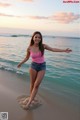 A woman standing in the ocean with her arms outstretched.