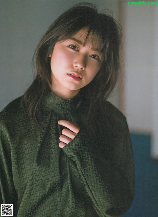 A woman in a green sweater is posing for a picture.