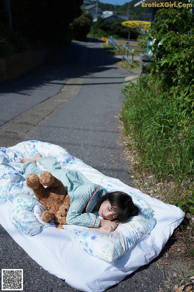 A little girl laying on a blanket with a teddy bear.