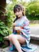 A woman in a blue kimono sitting on a bench.