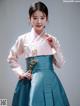 A woman in a blue and pink hanbok poses for a picture.