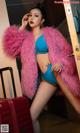 A woman in a blue bikini and a pink fur coat.