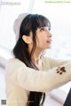 A woman with long black hair wearing a beige hat.