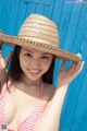 A woman in a bikini and a straw hat posing for a picture.